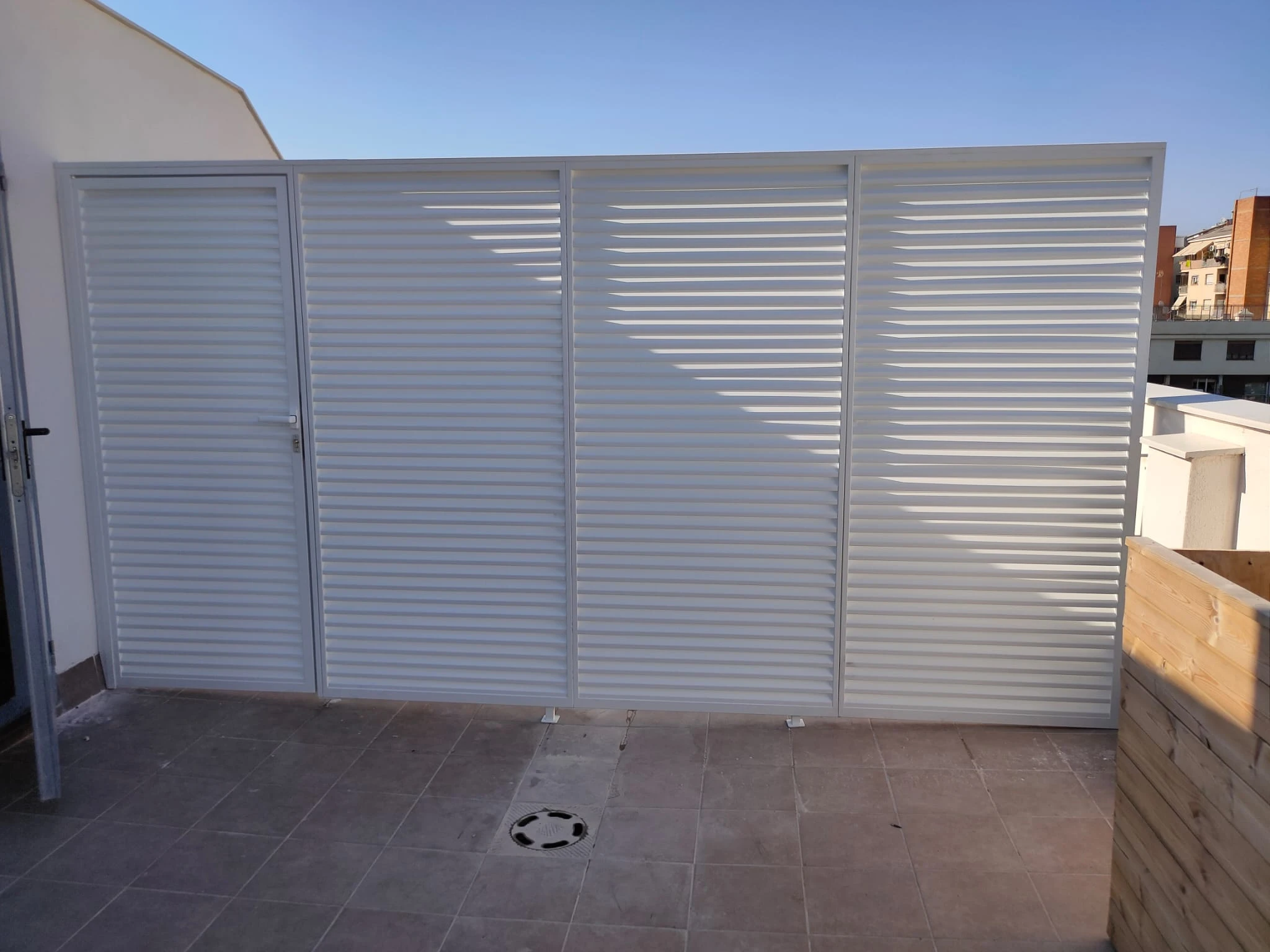 Separador de azotea con puerta integrada y lamas horizontales blancas