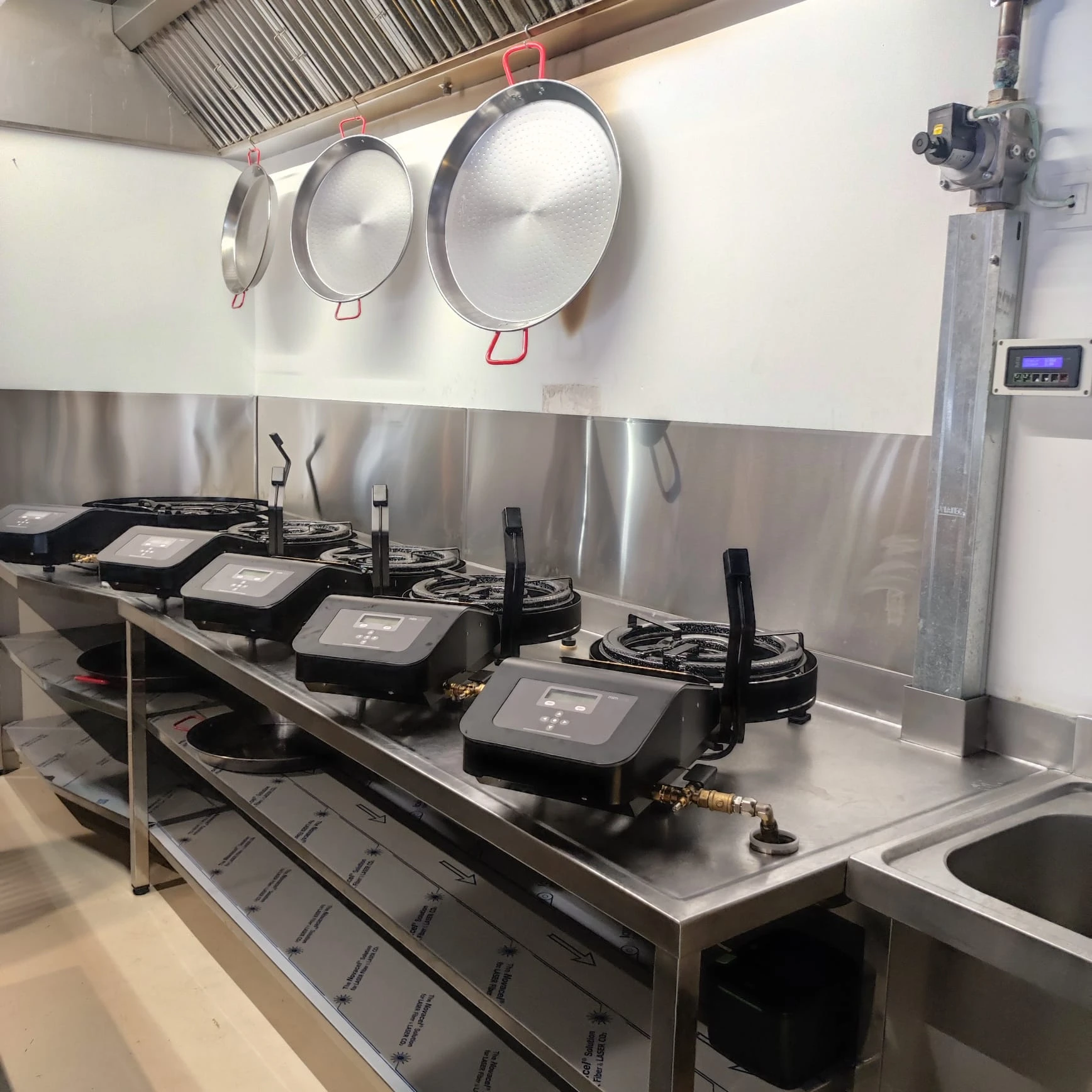Cocina industrial con paellero de varios fuegos y bandeja de acero inoxidable