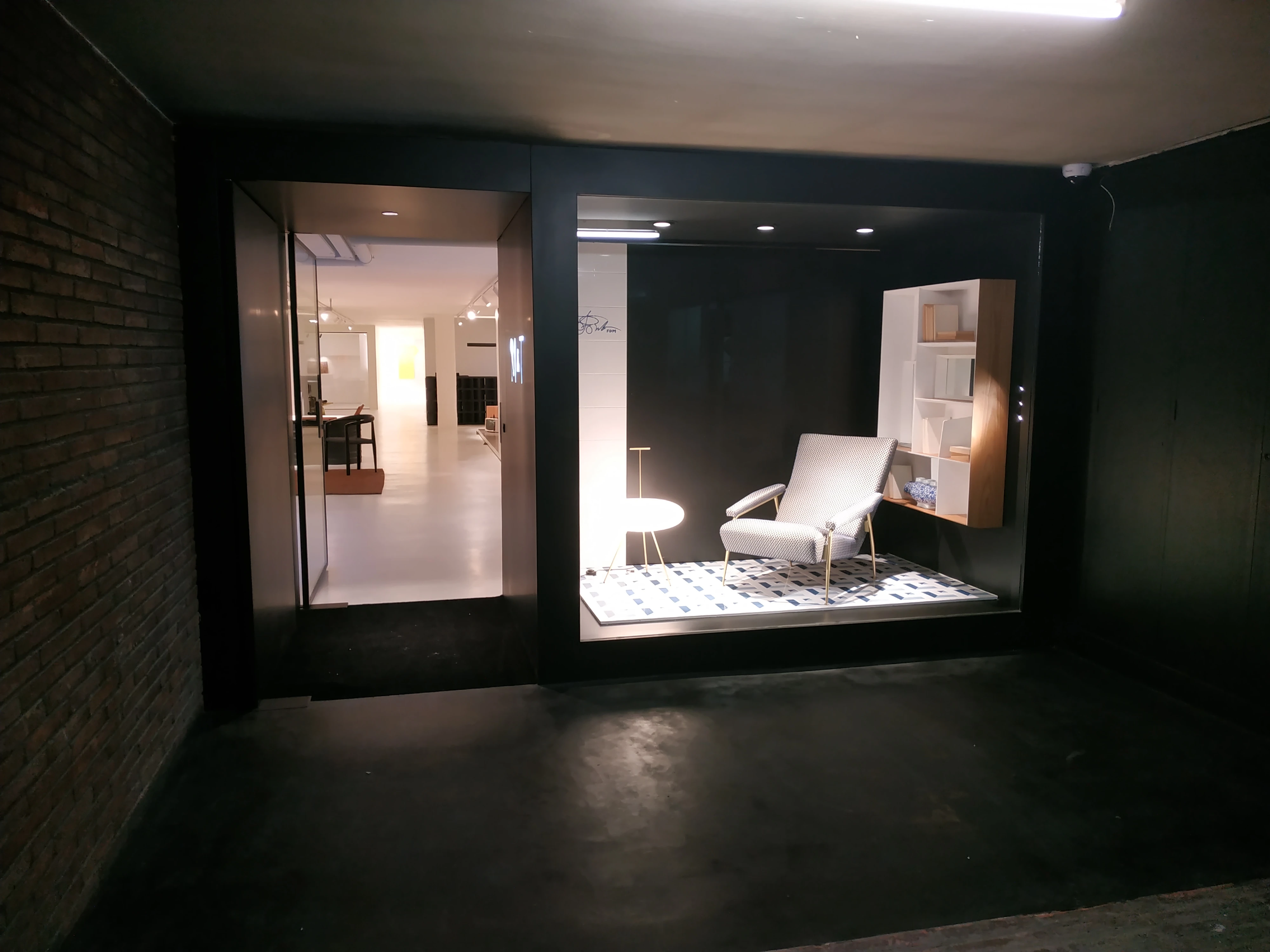 Entrada de comercio con vitrina iluminada y carpintería metálica negra